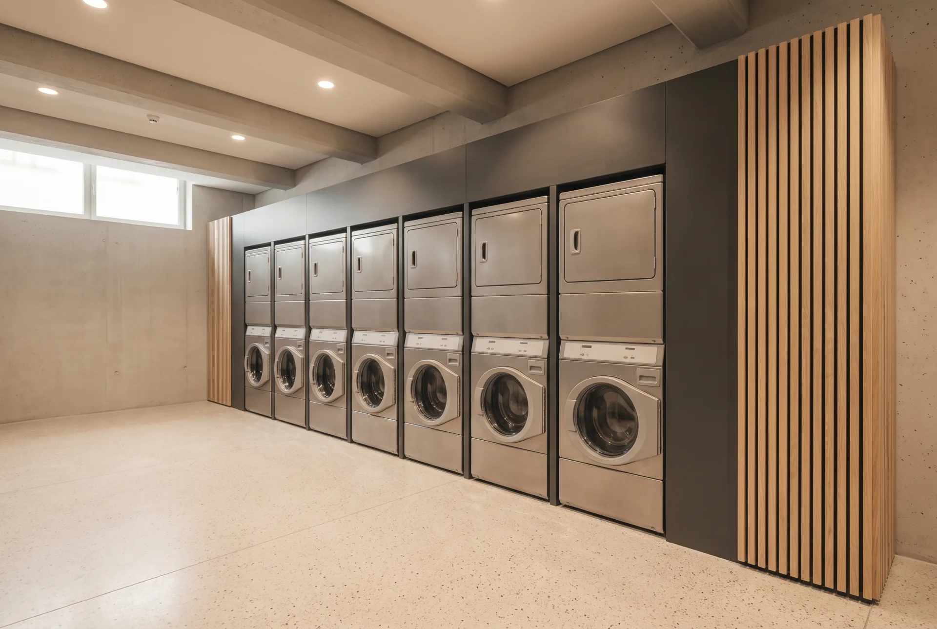 A bank of twelve stacked commercial dryers set into a charcoal steel surround running the length of the wall.